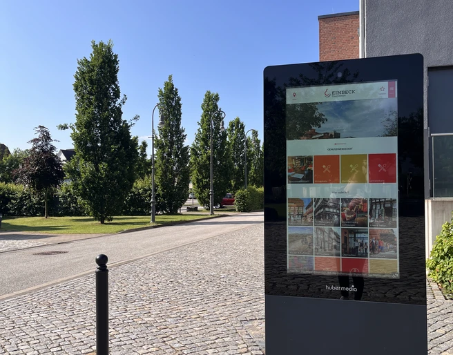 Infostele PS.SPEICHER Digitale Infostele vor dem PS.SPEICHER in Einbeck bei Sonnenschein. Im Hintergrund der Parkplatz des PS.SPEICHER mit Begrünung und Bäumen.