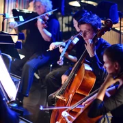 Mitglieder des Sinfonieorchesters Aachen spielen konzentriert ihre Instrumente unter stimmungsvollem Licht.