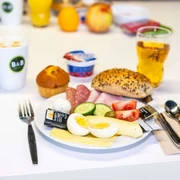Frühstück im B&B HOTEL Düsseldorf-Hilden Ein Teller mit frischem Frühstück: Aufschnitt, belegtes Brötchen, Heißgetränk und Saft im Hintergrund.