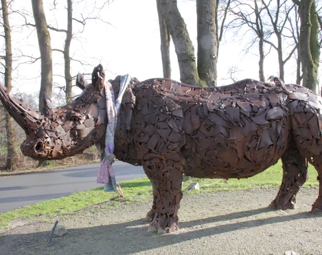 Nashorn-Spohle2-DerWiefelsteder.jpeg Eine beeindruckende Nashorn-Skulptur aus Metallteilen steht im Freien, umgeben von kahlen Bäumen.