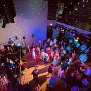 Hafendorf-Eröffnungsfeier Das Bild zeigt einen Raum mit vielen tanzenden Besuchern der Hafendorf Eröffnungsfeier im Hafentheater HAIN.
