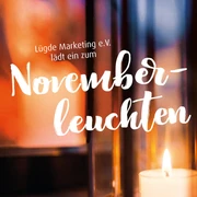 Kerze in Laterne strahlt warmes Licht aus, Hintergrund zeigt Einladung zu "Novemberleuchten".