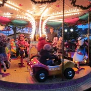 Kinder genießen eine fröhliche Fahrt auf einem hell erleuchteten Karussell bei einem Weihnachtsmarkt.
