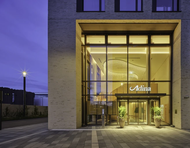 Adina-Hotel-Cologne Eingang des Adina Hotels in Köln mit heller Beleuchtung und moderner Architektur.Entrance to the Adina Hotel in Cologne with bright lighting and modern architecture.