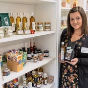 Regionale Produkte in der Tourist-Information Rochlitz Zu sehen ist Frau Uhlmann, die vor einem Schrank gefüllt mit regionalen Produkten aus der Region, in der Touristinformation Rochlitzer Muldental steht.