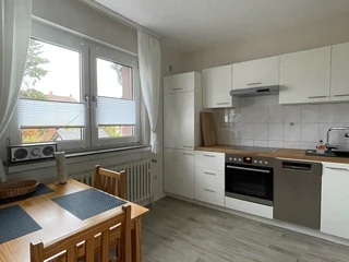 fewo_hermanns_kueche.jpg Moderne Küche mit Esstisch für vier Personen, hellen Fronten, großem Fenster und Laminatboden.