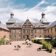 Innenhof vom Schloss Hugenpoet in Essen Historisches Schloss mit Innenhof in Essen, umgeben von Natur, bietet Sitzmöglichkeiten im Freien.