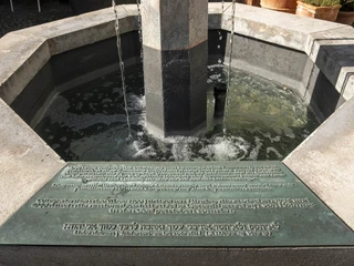 Lion Fountain Sechseckiger Steinbrunnen mit Wasserfluss, hebräische Inschrift auf Plakette im Vordergrund.Hexagonal stone fountain with flowing water, Hebrew inscription on plaque in the foreground.
