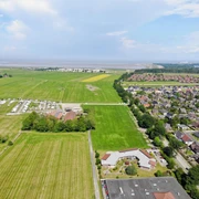 Luftansicht des Cmampingplatzes, geradeaus das Meer und rechts der Ort Hooksiel