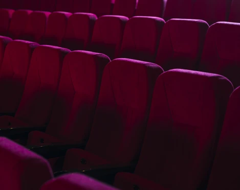 Kino-Sitze Reihen von weichen, roten Sesseln in einem leeren Kinosaal, die einladend auf Besucher warten.