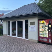 Feuerwehrmuseum Papstdorf mit Proviantomat Kleines Gebäude mit Schieferdach, daneben ein roter Automat mit beleuchteten Flaschen und Snacks.