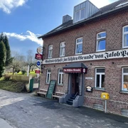 Der Kühle Grund Haan Das Gasthaus bietet traditionelle Küche in einem historischen Backsteingebäude mit rotem Eingang.