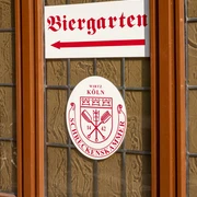 Brewery Schreckenskammer Ein Fenster des Brauhauses Schreckenskammer in Köln mit einem Schild, das auf den Biergarten hinweist.A window of the "Brauhaus Schreckenskammer" brewery in Cologne with a sign pointing towards the beer garden.
