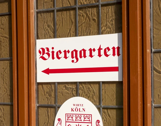 Brewery Schreckenskammer Ein Fenster des Brauhauses Schreckenskammer in Köln mit einem Schild, das auf den Biergarten hinweist.A window of the "Brauhaus Schreckenskammer" brewery in Cologne with a sign pointing towards the beer garden.