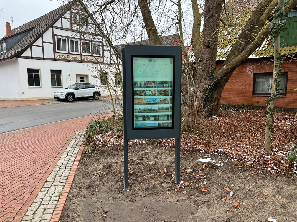 Infoterminal Steyerberg Infoterminal Steyerberg zeigt einen digitalen Bildschirm vor einem Fachwerkgebäude an einer Straßenecke an.