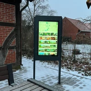 Infoterminal Landesbergen  Ein moderner Infoterminal mit leuchtendem Display im Außenbereich, umgeben von schneebedeckten Strukturen.