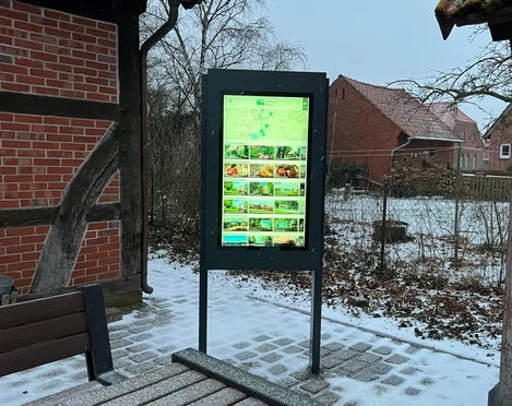 Infoterminal Landesbergen  Ein moderner Infoterminal mit leuchtendem Display im Außenbereich, umgeben von schneebedeckten Strukturen.