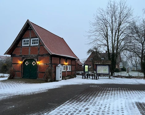 Infoterminal Landesbergen  Historisches Fachwerkgebäude am Infoterminal Landesbergen mit schneebedecktem Hof und kahlen Bäumen.