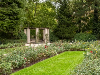 Rose Garden at Fort X Der Rosengarten am Fort X in Köln erstreckt sich unter hohen Bäumen und bietet einen Pavillon, umgeben von bunten Rosenblüten und gepflegten Rasenflächen.The rose garden at Fort X in Cologne stretches under tall trees and features a pavilion surrounded by colorful rose blossoms and manicured lawns.