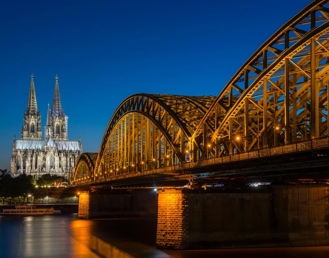 Hohenzollern Bridge Der Kölner Dom, erleuchtet in der Nacht, erhebt sich majestätisch neben der Hohenzollernbrücke, die über den Rhein führt.Cologne Cathedral, illuminated at night, rises majestically next to the Hohenzollern Bridge, which crosses the Rhine.