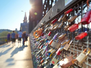 Hohenzollern Bridge Das Bild zeigt zahlreiche bunte Liebesschlösser, die eng an einem metallenen Gitter hängen, mit der Kathedrale Kölns im Hintergrund bei Sonnenschein.The picture shows numerous colorful love locks hanging closely on a metal lattice, with Cologne Cathedral in the background in the sunshine.