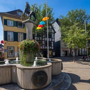 Löwenbrunnen auf dem Marktplatz in Ratingen  Löwenbrunnen auf Ratingens Marktplatz mit Springbrunnen, Säule und Löwenstatue im lichtdurchfluteten Umfeld.