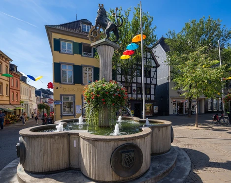 Löwenbrunnen auf dem Marktplatz in Ratingen  Löwenbrunnen auf Ratingens Marktplatz mit Springbrunnen, Säule und Löwenstatue im lichtdurchfluteten Umfeld.