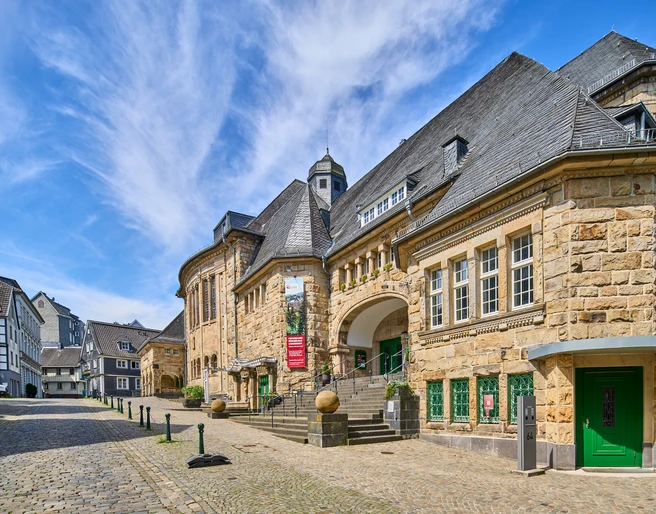 Historisches Bürgerhaus in Velbert-Langenberg Historisches Gebäude aus Sandstein mit markantem Schieferdach und grünen Türen in Velbert-Langenberg.