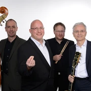 Jörg Hegemann Trio & Rolf Marx Vier Musiker in formeller Kleidung lächeln, mit Klavier, Gitarre, Kontrabass und Schlagzeug.