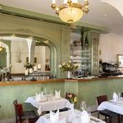 Restaurant Der vierte König Ein stilvoll eingerichteter Speiseraum mit grüner Wandverkleidung und elegant gedeckten Tischen.A stylishly furnished dining room with green wall paneling and elegantly laid tables.