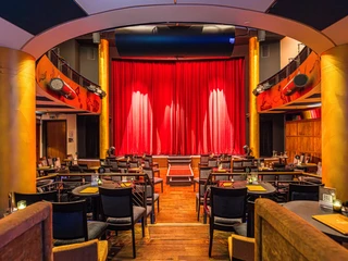 Varietésaal im Krystallpalast Varieté Leipzig - Abendveranstaltungen in Leipzig Blick auf die Bühne mit rotem Vorhang im Varietésaal des Krystallpalast Varieté Leipzig mit zahlreichen Stühlen und Tischen bei heller Beleuchtung, Kultur, Abendveranstaltung