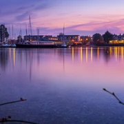 Cospudener See mit Sauna im See - Wellness in Leipzig und Region Der rosa und lila gefärbte Himmel spiegelt sich im Cospudener See, Am Pier liegen einige Segelboote an und die Sauna im See ist hell erleuchtet, Erholung, Wellness, Ausflug, Leizpiger Neuseenland
