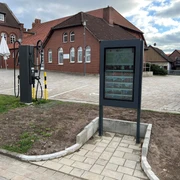Infoterminal Rehburg  Infoterminal vor roten Backsteingebäuden mit Kopfsteinpflaster und Fahrradzubehör auf einem Platz.