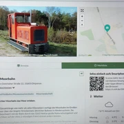 Infoterminal Diepenau  Ein moderner Infoterminal zeigt die Uchter Moorbahn, eine historische kleine rote Lokomotive.