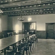 rathaus_i_kreishaus_situngssaal_1925_stadtarchiv_halle_westf._b.jpg Historischer Konferenzraum mit Holzdecke, großem Tisch, vielen Stühlen und einem Fenster.