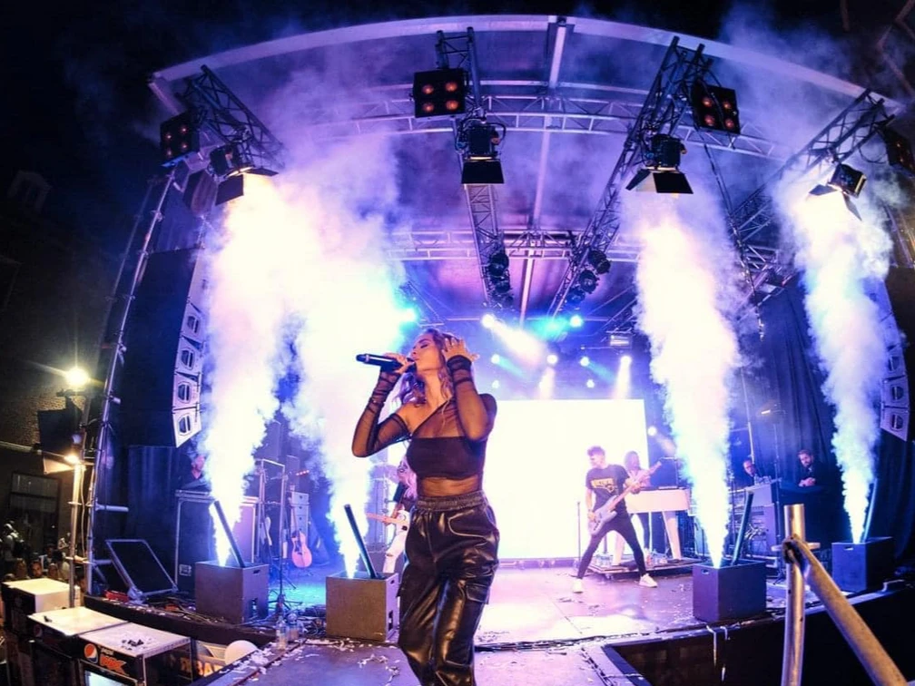koenigsplein.jpeg Eine Sängerin performt auf einer Bühne bei farbigem Licht und Rauch vor einem begeisterten Publikum.A singer performs on a stage with colored light and smoke in front of an enthusiastic audience.Een zangeres treedt op op een podium met gekleurd licht en rook voor een enthousiast publiek.