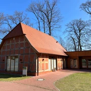 Rövers Schafstall Backsteinfachwerkhaus mit rotem Satteldach, umgeben von kahlen Bäumen und sonnigem, blauem Himmel.