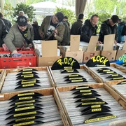 Schallplattenbörse 1 (c) Agentur Lauber.jpg Auf einem Tisch stehen Holzkisten mit aufgereihten Schallplatten, die durch gelbe Schilder nach Genre geordnet sind. Einige Personen stöbern interessiert.