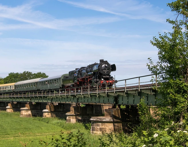 Eisenbahnmuseum Leipzig - Dampffahrten nach Kössern Eine Dampfbahn überquert bei ihrer sommerlichen Fahrt durch die Region Leipzig die Eisenbahnbrücke in Kössern