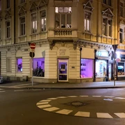 Modularfield Der Eingangsbereich eines Eckhauses bei Nacht, beleuchtet von lilafarbenem Licht.The entrance area of a corner house at night, illuminated by purple light.