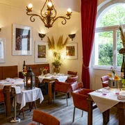Grubers Restaurant Gemütlich eingerichtetes Restaurant mit roten Lederstühlen und verschnörkelndem Kronleuchter.Comfortably furnished restaurant with red leather chairs and an ornate chandelier.