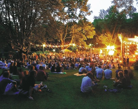 Die Freilichtbühne in der Mülheimer Altstadt Freilichtbühne in Mülheim an der Ruhr bei Abenddämmerung, mit Publikum in dichter Baumkulisse.