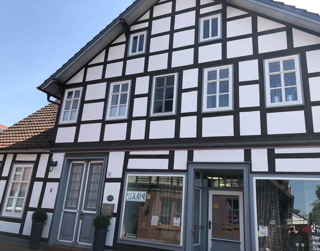 Gästezimmer Anna und Heini Historisches Fachwerkhaus mit weißer Fassade und dunklen Balken, großer Eingang und mehrere Fenster.