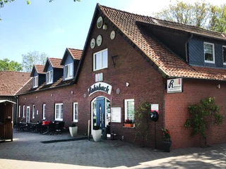 Rohrbach Glissen Ein rotes Backsteingebäude mit mehreren Gauben und einem überdachten Eingangsbereich auf einem gepflasterten Hof.