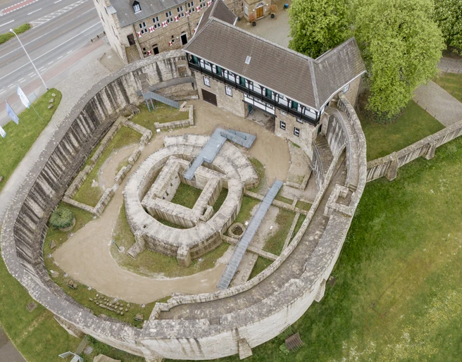 Schloß Broich, Mülheim an der Ruhr Mittelalterliche Festungsanlage mit Rundturm, umgeben von grünen Wiesen und Bäumen.