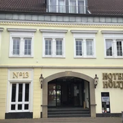 Historische Fassade von Hotel Höltje mit offenen Eingangsportal, darüber aufgereihte Fenster.