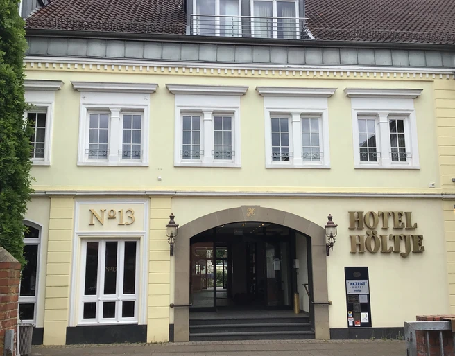 Hotel Höltje Historische Fassade von Hotel Höltje mit offenen Eingangsportal, darüber aufgereihte Fenster.