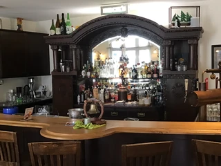 Hotel Höltje Ein holzgetäfelter Tresen vor einem gut bestückten, traditionellen Getränkeregal mit Spiegel.