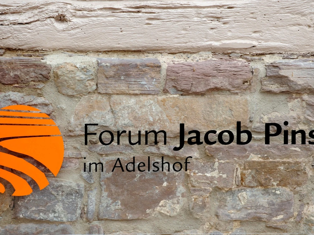 bild_pins_vakalender Forum Jacob Pins Schriftzug mit Logo auf einer rustikalen Bruchsteinmauer.