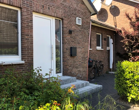 Appartement No. 16  Zwei Fahrräder stehen vor der Eingangstür eines Backsteinhauses mit kleinen Pflanzen im Vordergrund.